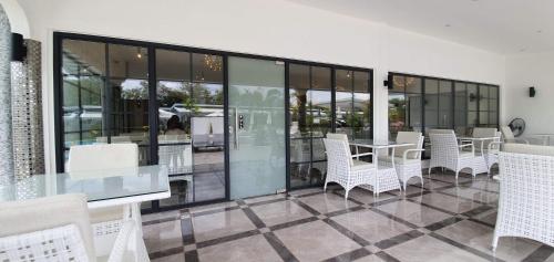 a patio with white chairs and a table and windows at Marina Point Bay Resort in Panglao