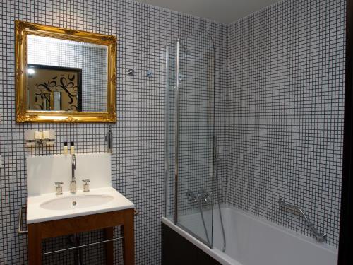 a bathroom with a sink and a tub and a mirror at EA Hotel Tereziánský dvůr in Hradec Králové