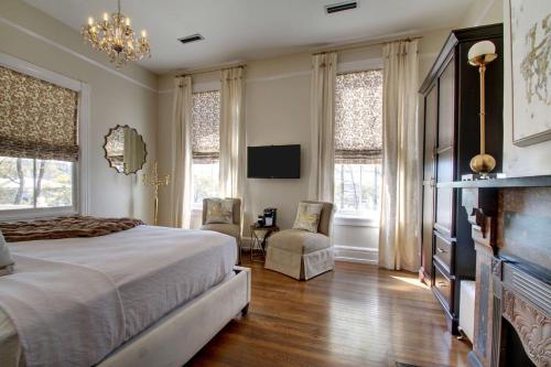 a bedroom with a bed and a fireplace and windows at Hotel Finial BW Premier Collection Oxford - Anniston in Anniston