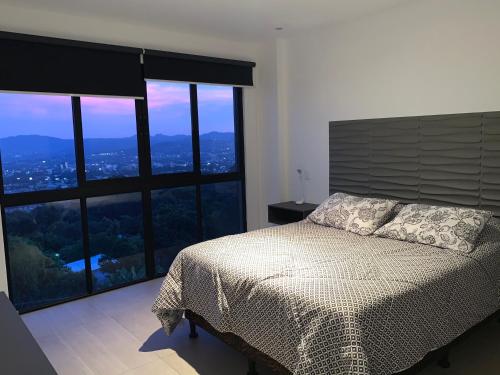 a bedroom with a bed and a large window at APARTAMENTO CON LA MEJOR VISTA DE SAN SALVADOR in San Salvador