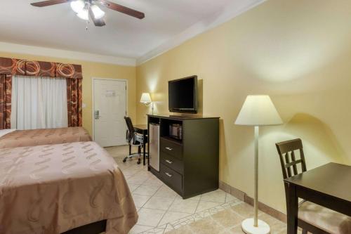 a bedroom with a bed and a desk with a television at Quality Inn & Suites at The Outlets Mercedes-Weslaco in Mercedes
