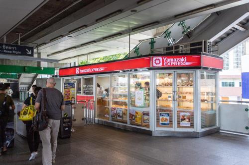a man standing in front of a food stand at an airport at U2 Large 2 Bedrooms 100m to BTS station in Bangkok