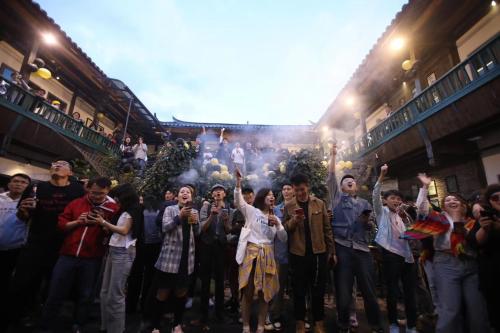 grupa ludzi stojących w tłumie z rękami w górze w obiekcie Lijiang Desti Youth Park Hostel w mieście Lijiang