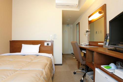 Habitación de hotel con cama y escritorio con ordenador en Hotel Route-Inn Ichinomiya Ekimae en Ichinomiya