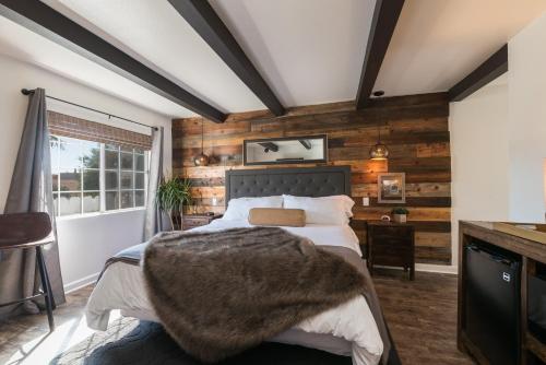 ein Schlafzimmer mit Holzwänden und ein Bett mit einer Decke in der Unterkunft Shell Beach Inn in Pismo Beach