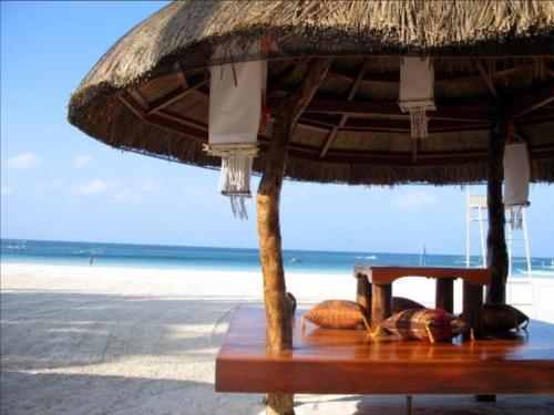a table with a straw umbrella on the beach at Sur Beach Resort Boracay in Boracay