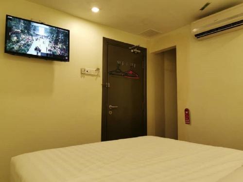 a room with a bed and a door with a television at Desa house hotel in Kampong Kepong