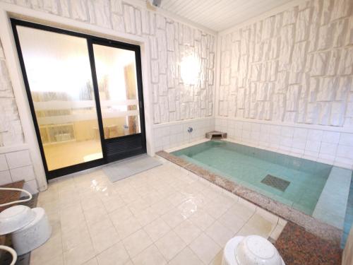 a large bathroom with a swimming pool with a window at Hotel Route-Inn Kani in Kani