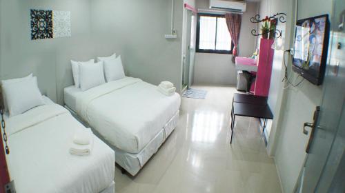 a small room with two beds and a table at Ma Non Nont Hotel & Apartment in Nonthaburi