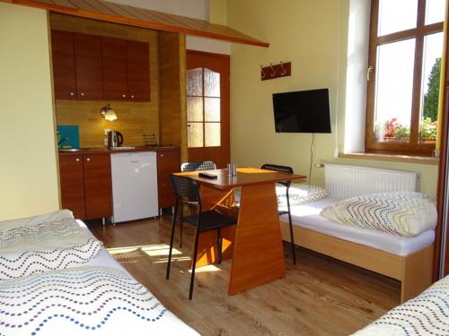 a room with two beds and a table and a kitchen at Noclegi "Marek i Karolina" in Cieszyn