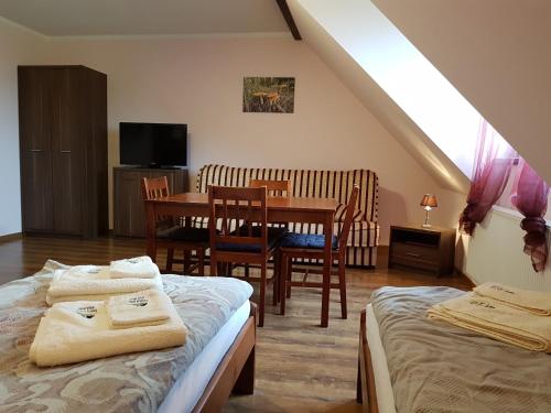 a room with two beds and a table and chairs at Kamienna Polana in Szczytna