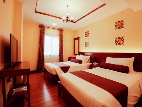 Habitación de hotel con 2 camas y TV en Sunlight Guest Hotel, Coron, Palawan, en Corón