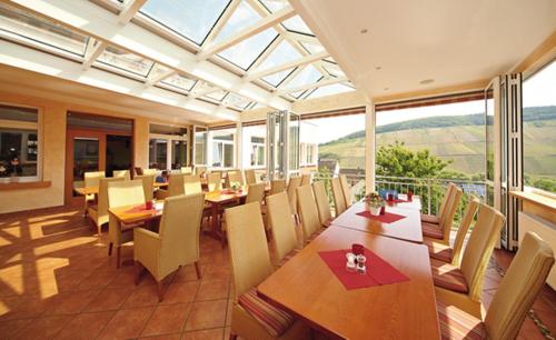 a dining room with tables and chairs and a large window at WeinBergHotel Nalbach in Reil