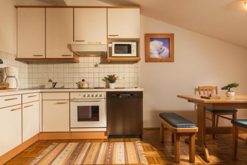 a kitchen with white appliances and a wooden table at Ferienwohnung Salzburg in Bruck an der Großglocknerstraße