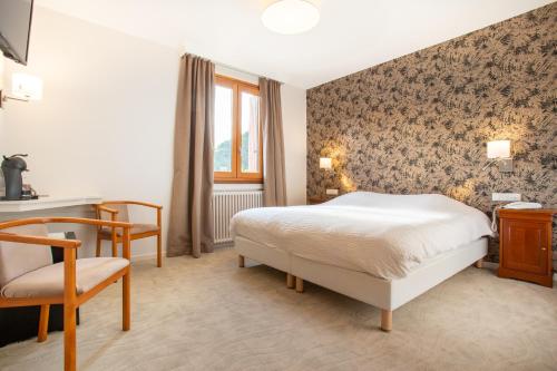 a bedroom with a bed and a desk and a chair at Logis Hotel Restaurant du Pont in Ambialet