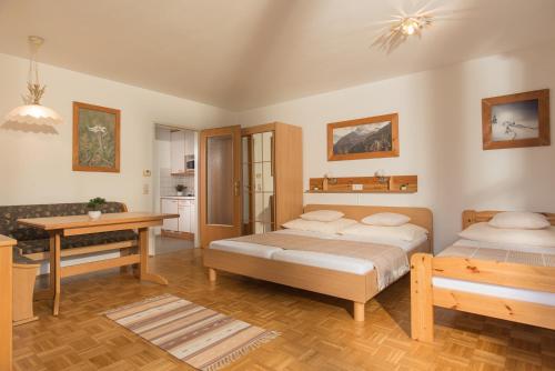 sypialnia z 2 łóżkami, biurkiem i stołem w obiekcie Ferienwohnung Salzburg w mieście Bruck an der Großglocknerstraße