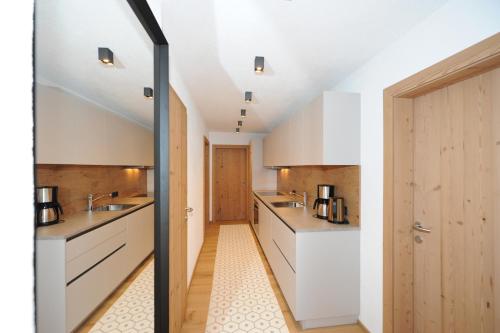 a kitchen with white cabinets and a sliding glass door at Ferienwohnungen Familie Niedermoser Stefan in Sankt Jakob in Haus