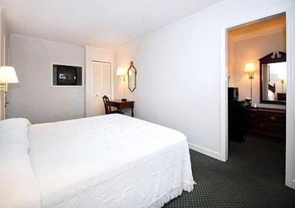 a bedroom with a white bed and a mirror at Ambassador Inn in Fayetteville