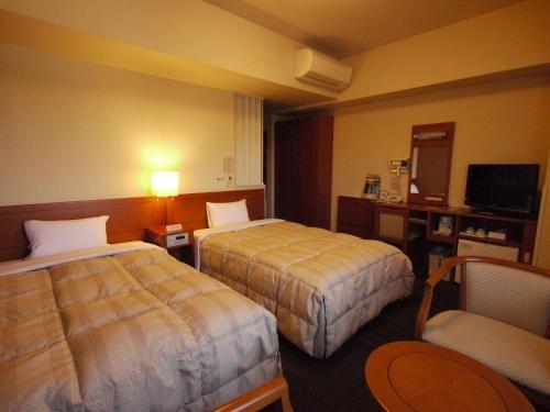 a hotel room with two beds and a desk at Hotel Route-Inn Suzuka in Suzuka