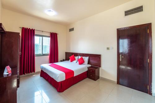 a bedroom with a large bed with red curtains at Al Reem Hotel Apartments in Sharjah