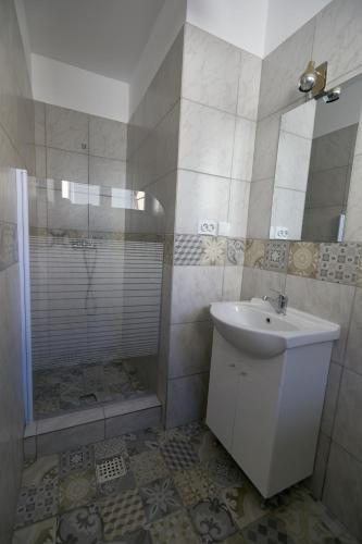 a white bathroom with a sink and a shower at Stanford Aparthotel in Bucharest