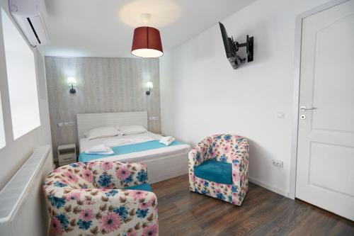 a bedroom with a bed and two chairs at Stanford Aparthotel in Bucharest