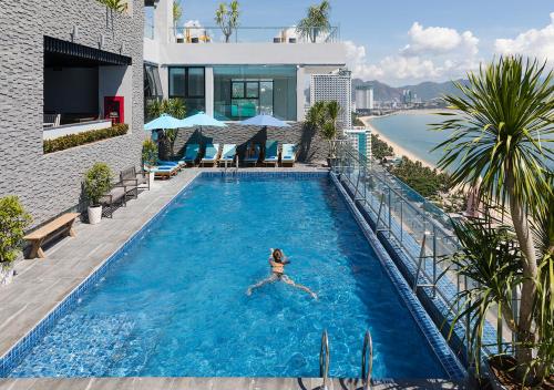 a woman swimming in a swimming pool next to a building at Maple Hotel & Apartment in Nha Trang