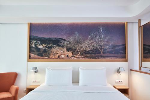 a bedroom with a bed with a painting on the wall at Olive Green Hotel in Heraklio