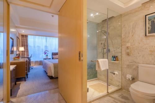 a bathroom with a shower and a toilet and a bed at Zhejiang Hotel in Hangzhou