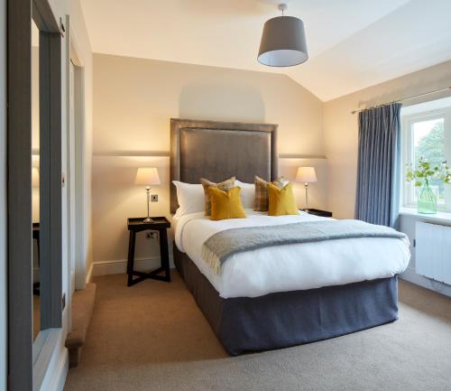 1 dormitorio con 1 cama grande con almohadas amarillas en Rooms by Bistrot Pierre at The Crescent Inn, en Ilkley