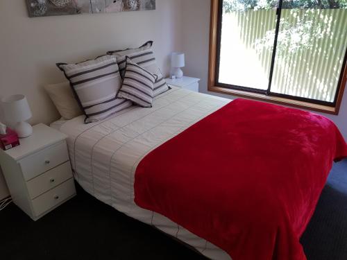 um quarto com uma cama grande, um cobertor vermelho e almofadas em Portarlington beach shack 50 metres to the water em Portarlington