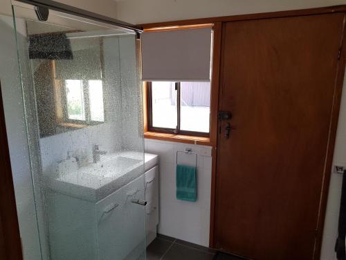 uma casa de banho com um lavatório e uma porta de duche em vidro. em Portarlington beach shack 50 metres to the water em Portarlington