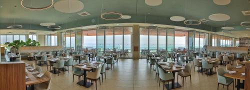White Lagoon Resort - All Inclusive في كافارنا: غرفة طعام مع طاولات وكراسي ونوافذ