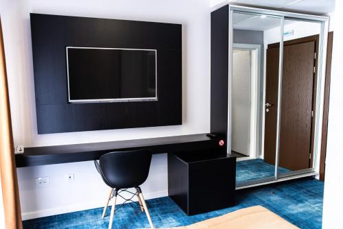a room with a tv and a chair and a mirror at Hotel Biss in Zenica