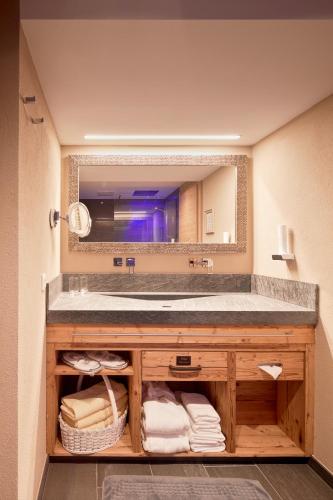 a bathroom with a sink and a large mirror at Hotel Tirol in Ischgl