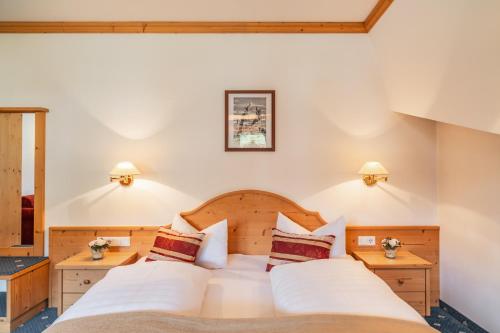 a bedroom with two beds and two night stands at Hotel Erna in Colle Isarco