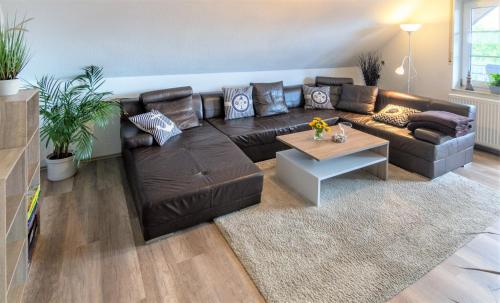 a living room with a brown leather couch and a table at Nordsee-Nest in Ostochtersum