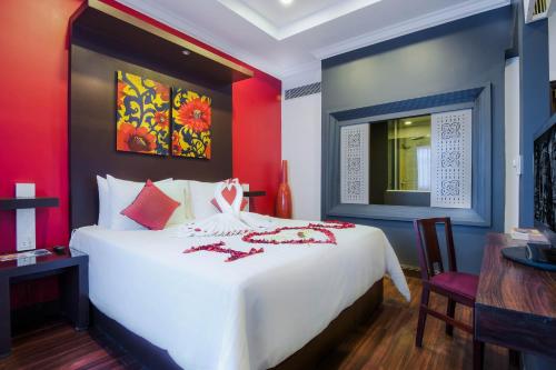 a bedroom with a large white bed with red walls at Memoire d' Angkor Boutique Hotel in Siem Reap