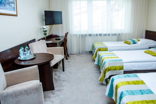 a hotel room with two beds and a table and chairs at Hotel Alexandra in Pobiedziska