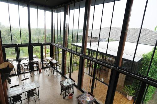 a room with tables and chairs and large windows at Hug Jang Loei Garden & Resort in Ban Na Dan
