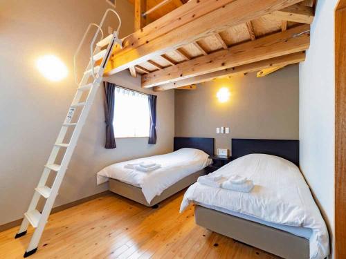 a bedroom with two beds and a ladder at Beach Resort Hotel Kalakaua in Onna