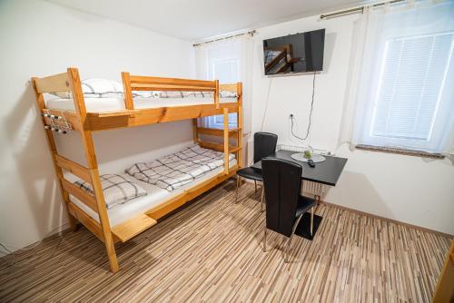 a room with two bunk beds and a desk and a table at Rooms at Trimček in Sevnica