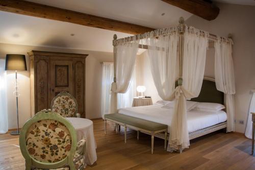 a bedroom with a canopy bed and a chair at Hotel Villa Nabila in Reggiolo