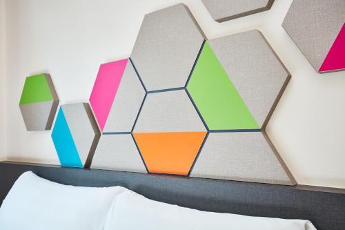 a bedroom with a colorful hexagonal wall above a bed at ibis budget Singapore Emerald in Singapore