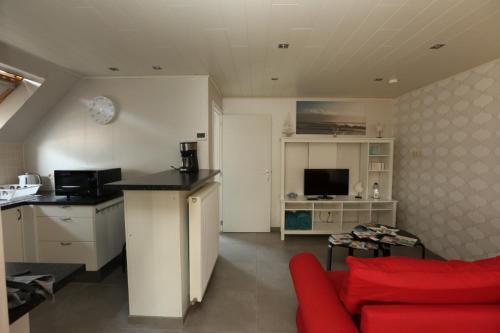 a living room with a red couch and a kitchen at de Zeester in Bredene-aan-Zee