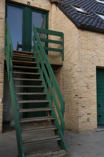 un escalier en métal vert à côté d'un bâtiment en briques dans l'établissement de Zeester, à Bredene-aan-Zee
