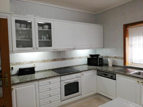 アヴェイロにあるLovely Apartment Aveiroのキッチン(白いキャビネット、コンロ付)