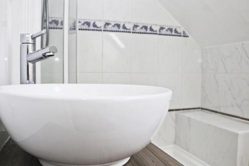 a white bathroom with a sink and a shower at BY THE BEACH Harlyn Bay in St Merryn