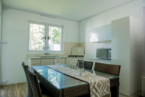 a kitchen with a glass table with chairs and a microwave at Khesha’s Villa in Riambel