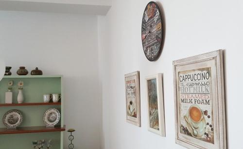 a clock hanging on a wall with pictures on it at Metro Suites in Tirana